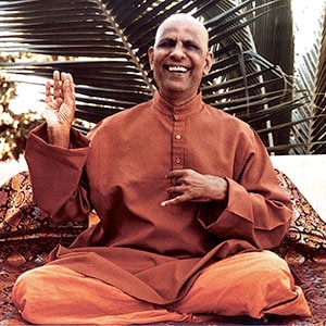 Swami Kripalvananda seated, smiling and wearing an orange robe.